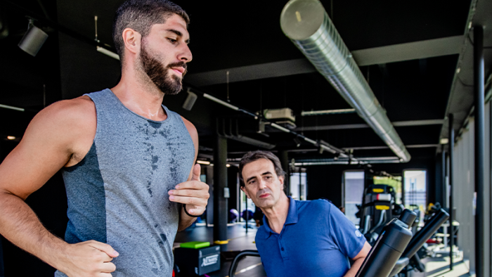 Un homme sportif court sur un tapis roulant sous l'observation d'un physiothérapeute du sport au Swiss Medical Network