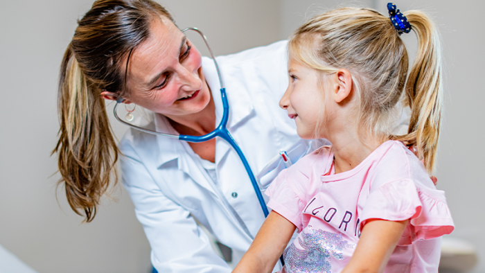 Médecin avec stéthoscope et fillette blonde effectuant un examen pédiatrique au Swiss Medical Network